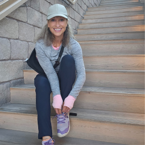 Joanna Hall smiling whilst sat on some stairs adjusting her trainer