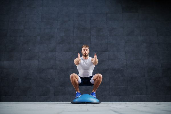 balance training on the bosu - Front view of man doing squat exercise on bosu ball.