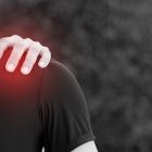Does your client have frozen shoulder? Image of someone holding their shoulder with pain radiating out from under their hand