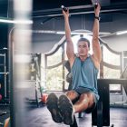 six strategies for training abs in extension - image of man doing a hanging leg raise in the gym