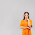 Unlocking emotional intelligence - we chat to Bianca Errigo. Here she is pictured in front of a grey background wearing a vibrant orange dress.