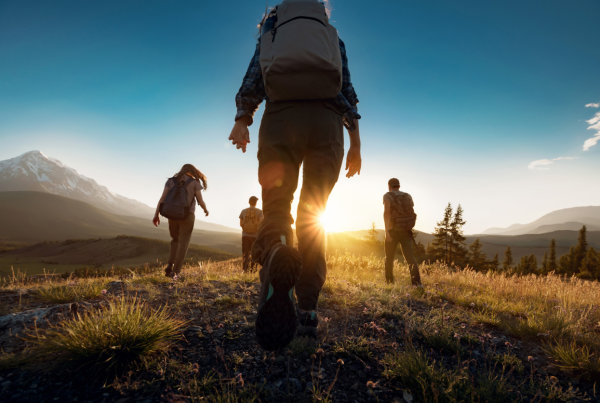 Group of people walking up a hill with the sun shining behind them - blog on how long distance hiking boosts wellbeing