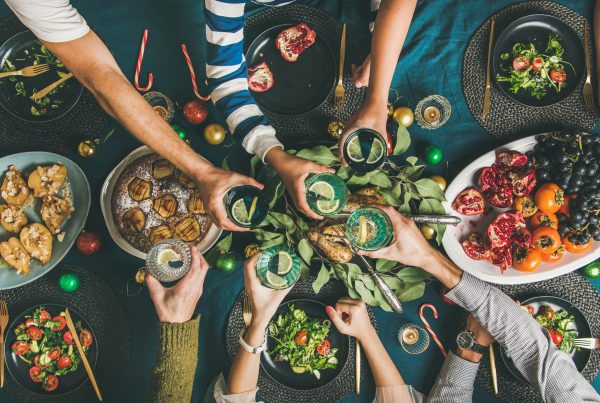 Flat-lay of human hands holding glasses with drinks, feasting and celebrating holiday together, top view - food combining part one