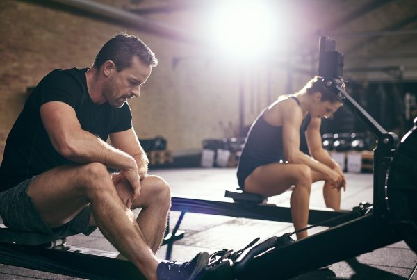 Two people taking break on rowing machine - blog on submaximal testing for hyrox rowing